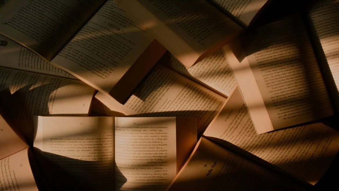 Pages ouvertes de livres sous lumière dorée, texture papier patinée évoquant lecture et nostalgie.