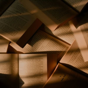 Pages ouvertes de livres sous lumière dorée, texture papier patinée évoquant lecture et nostalgie.
