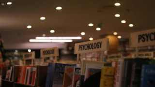 Rayon psychologie de librairie avec livres, étagères et éclairage chaleureux.