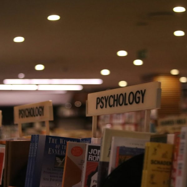 Rayon psychologie de librairie avec livres, étagères et éclairage chaleureux.