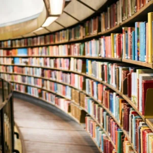 Salle de lecture circulaire, rayonnages courbes en bois et étagères remplies de livres.