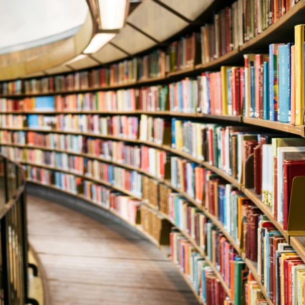 Salle de lecture circulaire, rayonnages courbes en bois et étagères remplies de livres.
