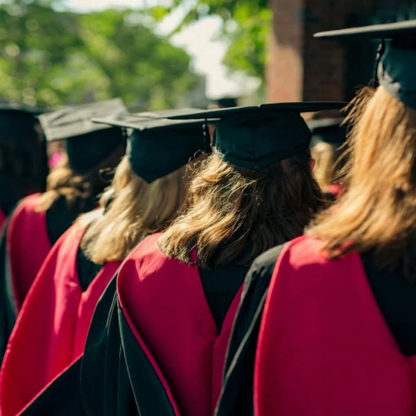 Remise de diplômes : procession détudiants en toges noires et capes rouges.