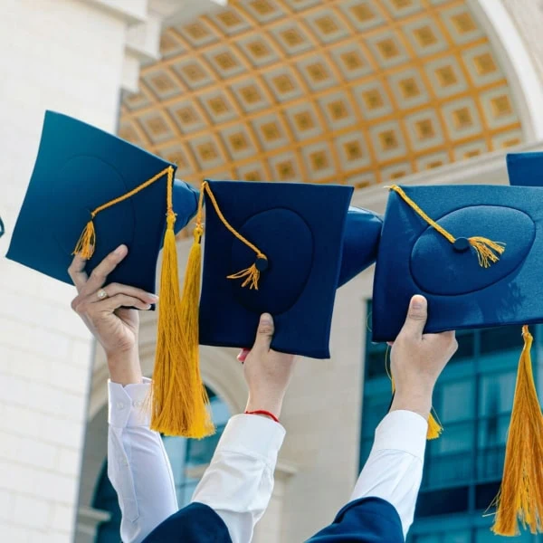 Remise de diplômes à luniversité, chapeaux bleu marine levés devant bâtiment classique.