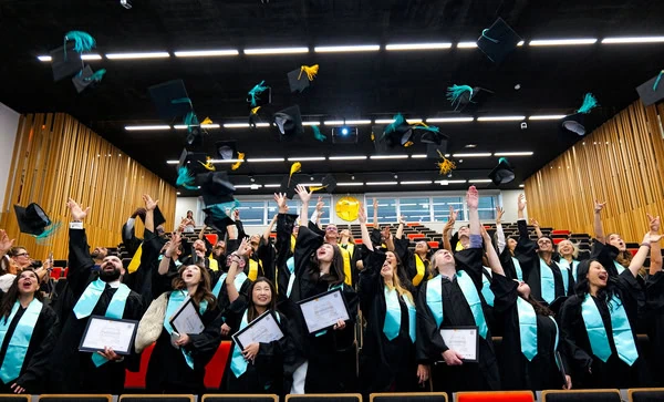 Remise de diplômes : diplômés lançant leurs chapeaux en lair dans un auditorium en liesse.