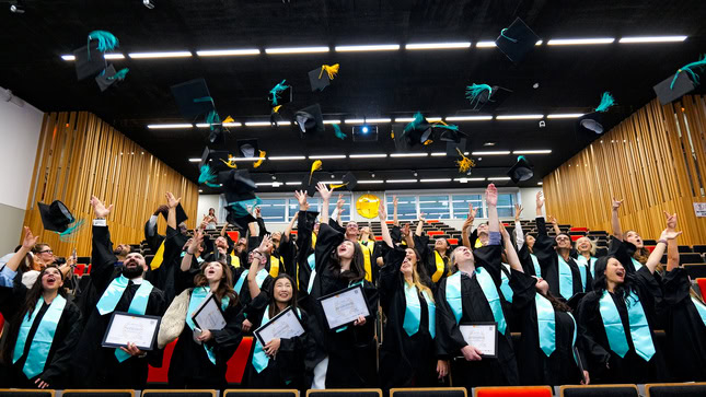 Remise de diplômes : diplômés lançant leurs chapeaux en lair dans un auditorium en liesse.
