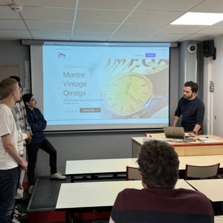 Présentation en salle de cours avec projection dune montre vintage, enseignant, étudiants et ordinateur.