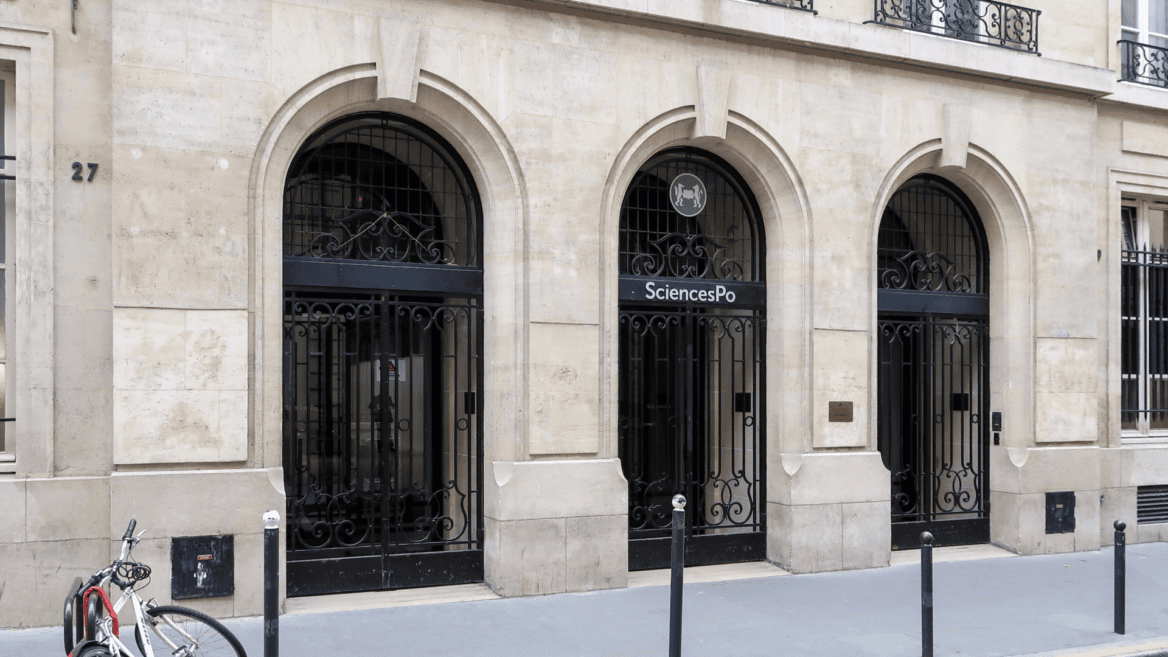 Entrée Sciences Po 27, façade en pierre avec trois arcades et grille en fer forgé.
