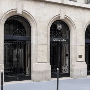 Entrée Sciences Po 27, façade en pierre avec trois arcades et grille en fer forgé.