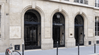 Entrée Sciences Po 27, façade en pierre avec trois arcades et grille en fer forgé.