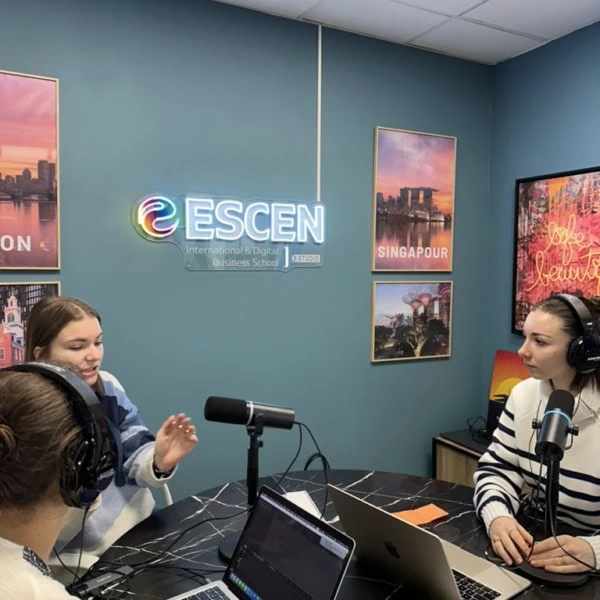 Studio podcast ESCEN moderne pour enregistrement avec microphones, animateurs et néon coloré.
