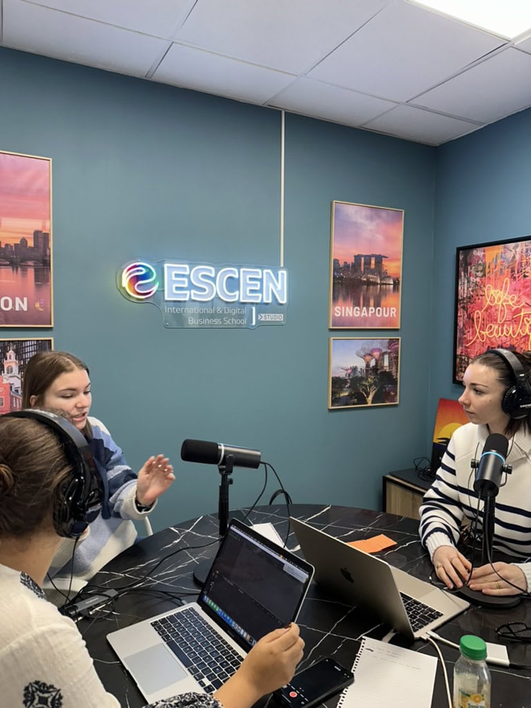 Studio podcast ESCEN moderne pour enregistrement avec microphones, animateurs et néon coloré.