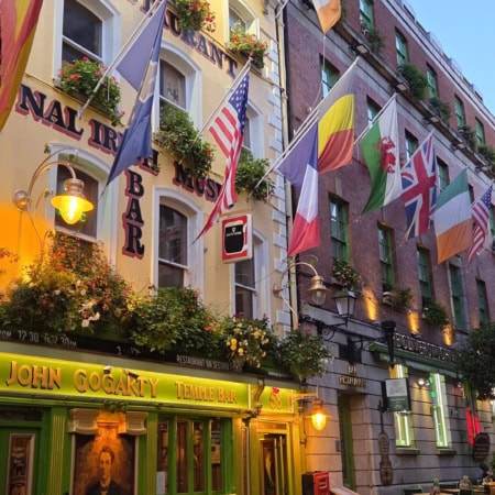Pub Temple Bar sur rue pavée, façades colorées, drapeaux et lanternes au crépuscule.