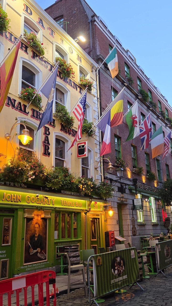 Pub Temple Bar sur rue pavée, façades colorées, drapeaux et lanternes au crépuscule.