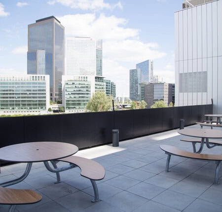 Toit-terrasse dentreprise avec tables rondes et vue sur lhorizon urbain de bureaux.
