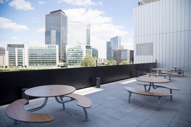 Toit-terrasse dentreprise avec tables rondes et vue sur lhorizon urbain de bureaux.