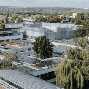 Toits avec panneaux solaires et végétalisés sur campus urbain moderne, bâtiments et arbres.