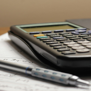 Calculatrice scientifique et stylo sur cahier ligné, ambiance étude bureau intime.