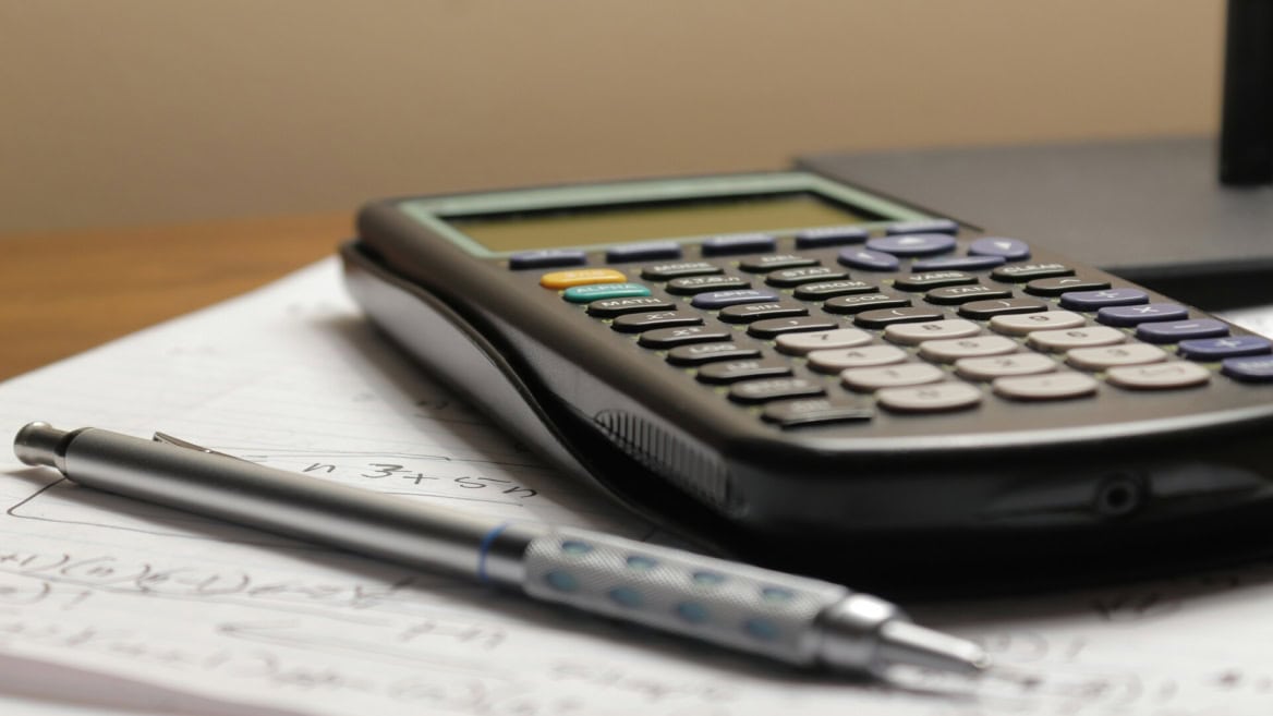 Calculatrice scientifique et stylo mécanique sur papier ligné, gros plan détude mathématiques.