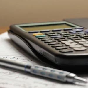 Calculatrice scientifique et stylo mécanique sur papier ligné, gros plan détude mathématiques.