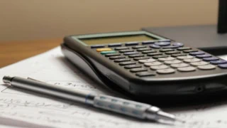 Calculatrice scientifique et stylo mécanique sur papier ligné, gros plan détude mathématiques.