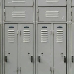 Casiers métalliques numérotés 19 à 26 dans un vestiaire scolaire, serrures visibles.