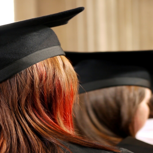 Chapeaux de diplômés noirs alignés sur cheveux bruns lors dune cérémonie de remise de diplômes.