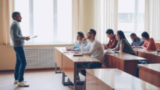 Enseignant donnant cours à des étudiants attentifs dans une salle de classe lumineuse.