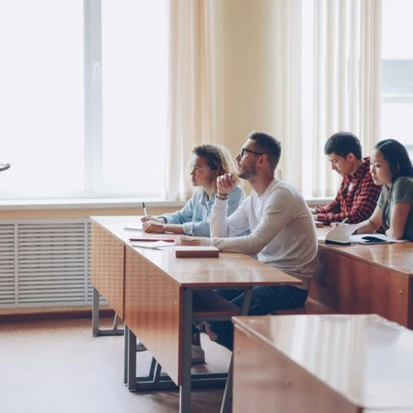 Enseignant donnant cours à des étudiants attentifs dans une salle de classe lumineuse.