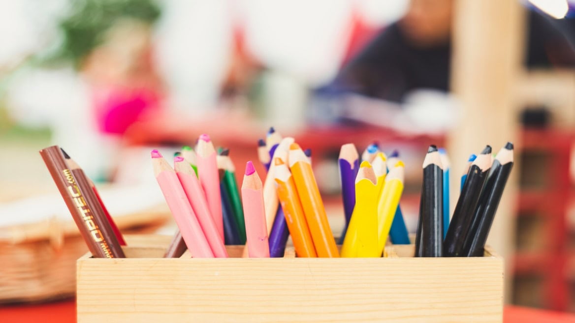 Crayons de couleur variés dans une boîte en bois pour atelier créatif.