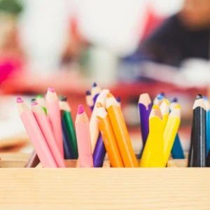 Crayons de couleur variés dans une boîte en bois pour atelier créatif.