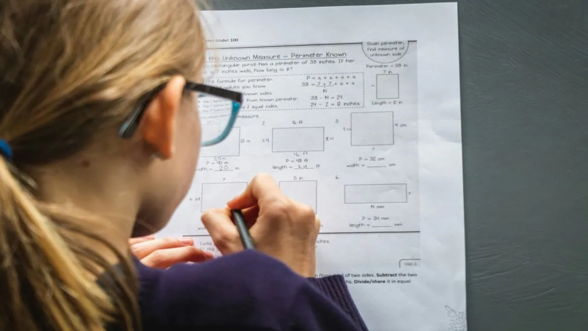 Élève écrivant des exercices de périmètre et mesures sur feuille de mathématiques avec crayon.
