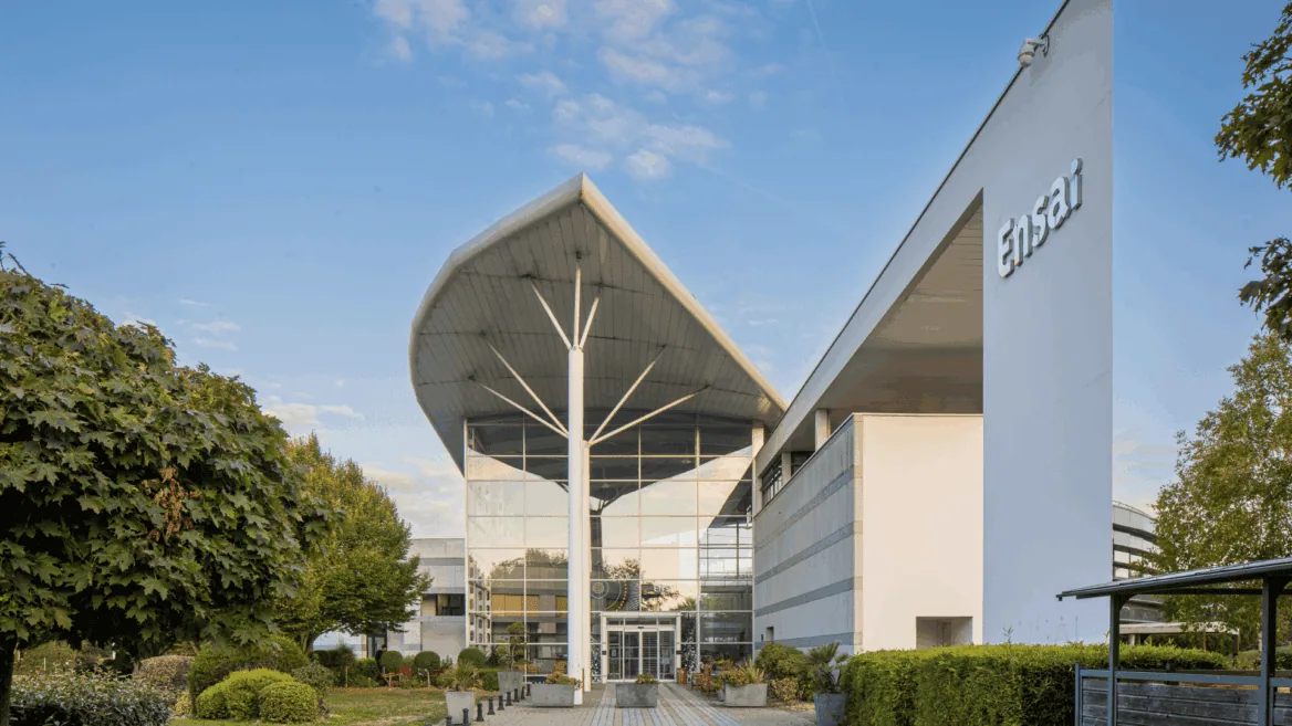 Entrée ENSAI : bâtiment contemporain avec grand auvent courbe et façade vitrée sur campus.
