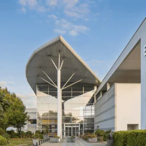 Entrée ENSAI : bâtiment contemporain avec grand auvent courbe et façade vitrée sur campus.