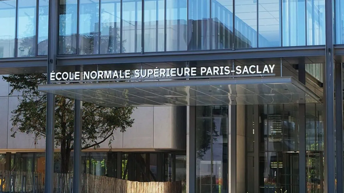 Entrée de lÉcole normale supérieure Paris‑Saclay : façade vitrée moderne et marquise métallique.