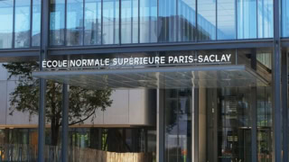 Entrée de lÉcole normale supérieure Paris‑Saclay : façade vitrée moderne et marquise métallique.