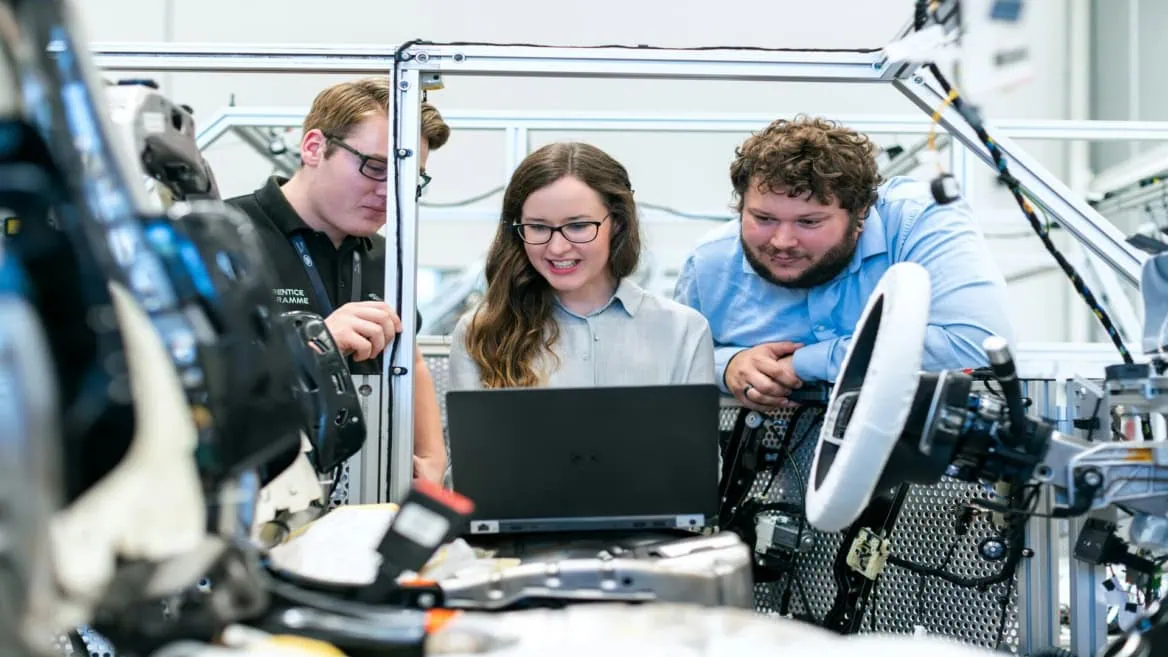 Équipe dingénieurs autour dun ordinateur portable testant prototype de véhicule, câblage et banc dessai.
