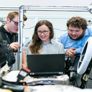 Équipe dingénieurs autour dun ordinateur portable testant prototype de véhicule, câblage et banc dessai.