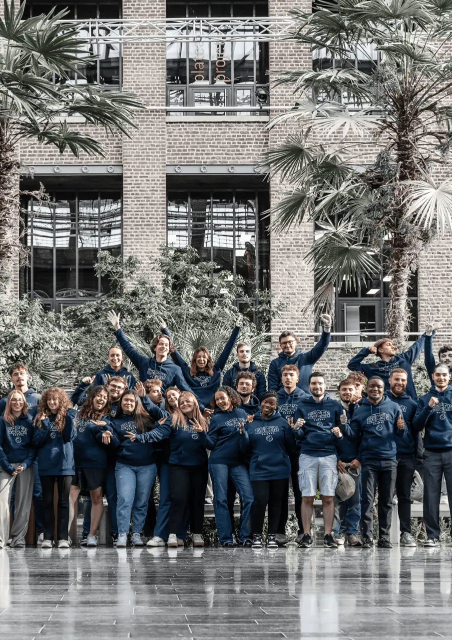 Groupe de jeunes en sweats à capuche devant façade en brique et palmiers.