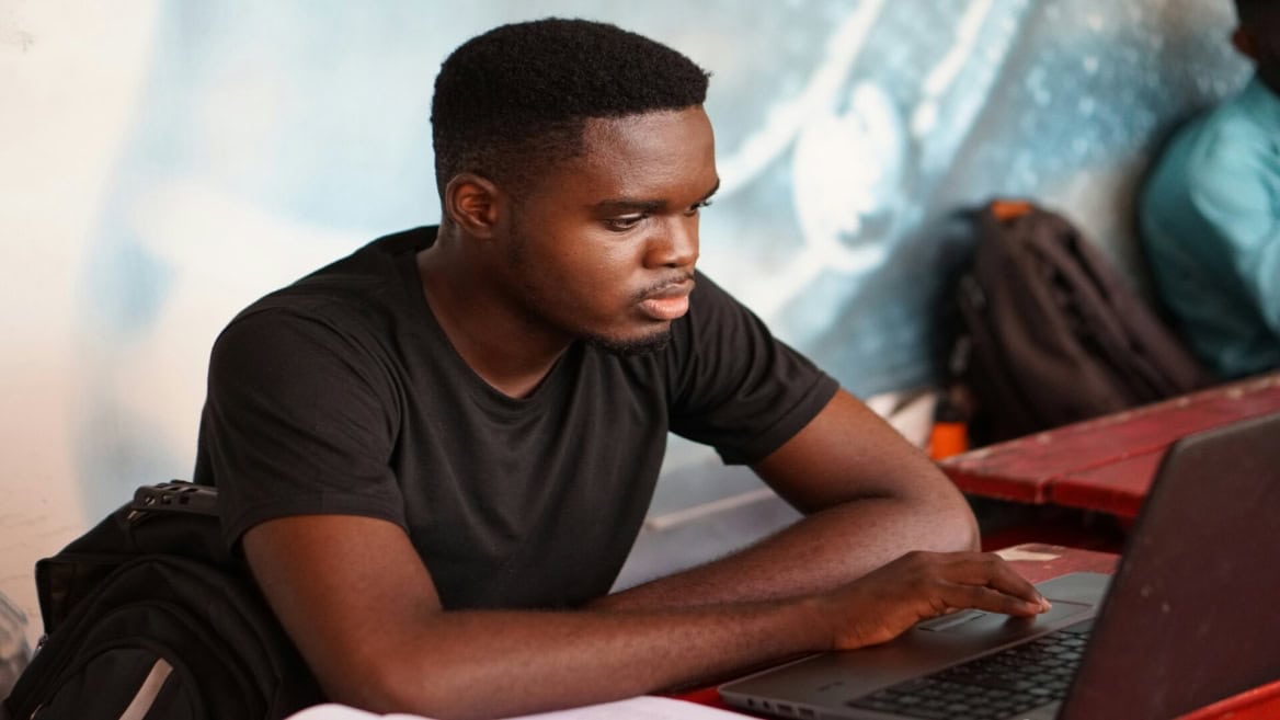 Jeune homme concentré sur ordinateur portable, étudiant en coworking.