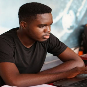 Jeune homme concentré sur ordinateur portable, étudiant en coworking.