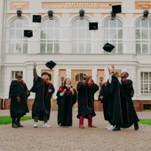 Étudiants diplômés lançant leurs toques sur le campus devant bâtiment académique.