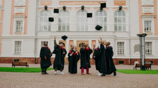 Étudiants diplômés lançant leurs toques sur le campus devant bâtiment académique.