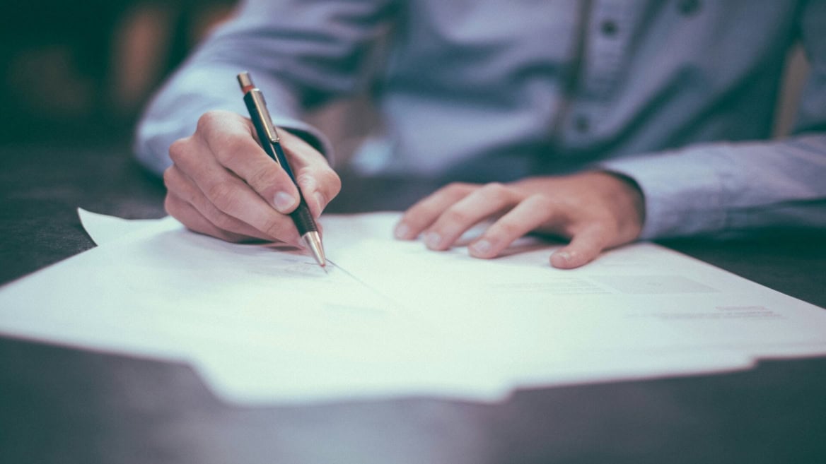 Mains signant un document au stylo sur table de bureau, signature professionnelle.