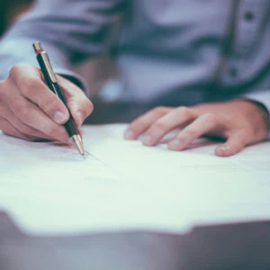 Mains signant un document au stylo sur table de bureau, signature professionnelle.