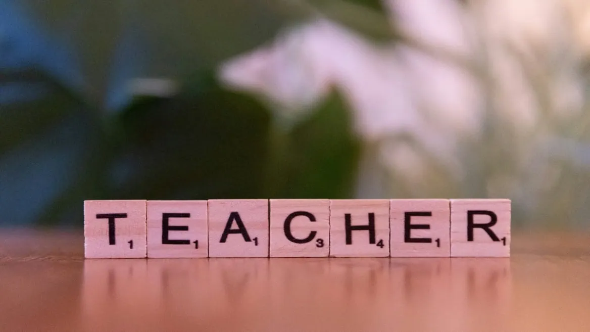 Gros plan de tuiles Scrabble en bois formant « TEACHER », mot enseignant et éducation.