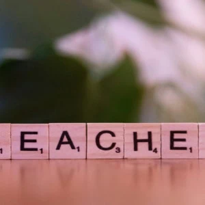 Gros plan de tuiles Scrabble en bois formant « TEACHER », mot enseignant et éducation.