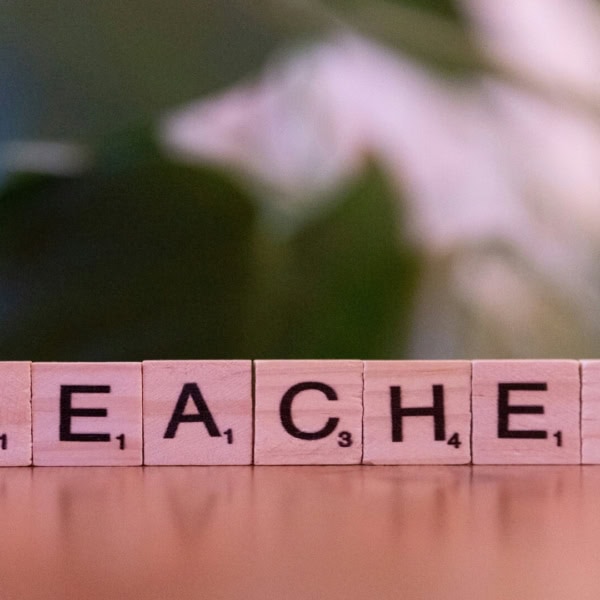 Gros plan de tuiles Scrabble en bois formant « TEACHER », mot enseignant et éducation.