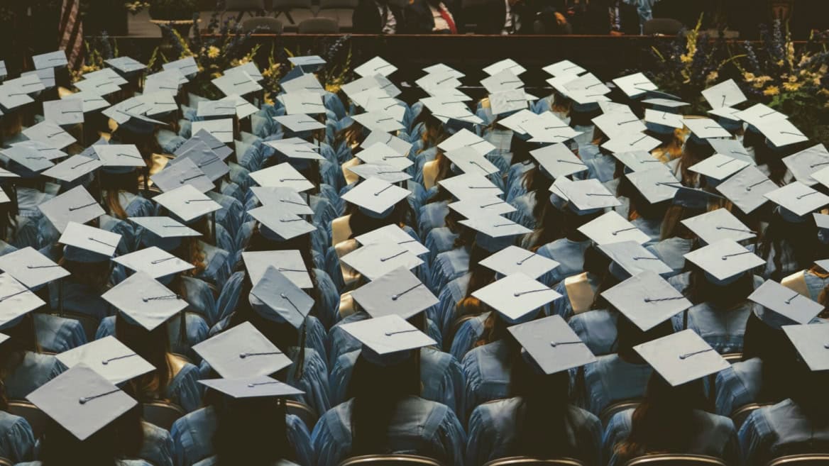 Vue plongeante de diplômés en toques et robes bleues alignés lors dune remise de diplômes.