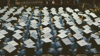 Vue plongeante de diplômés en toques et robes bleues alignés lors dune remise de diplômes.